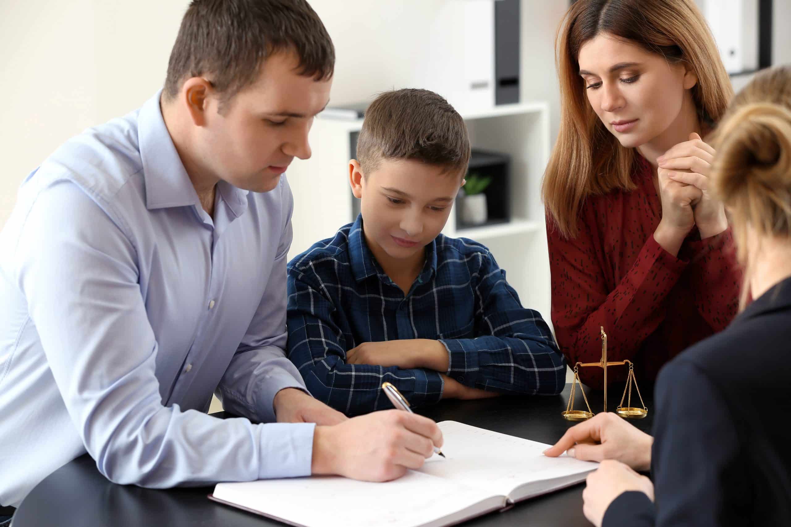 Divorced parents with their son visiting lawyer signing papers