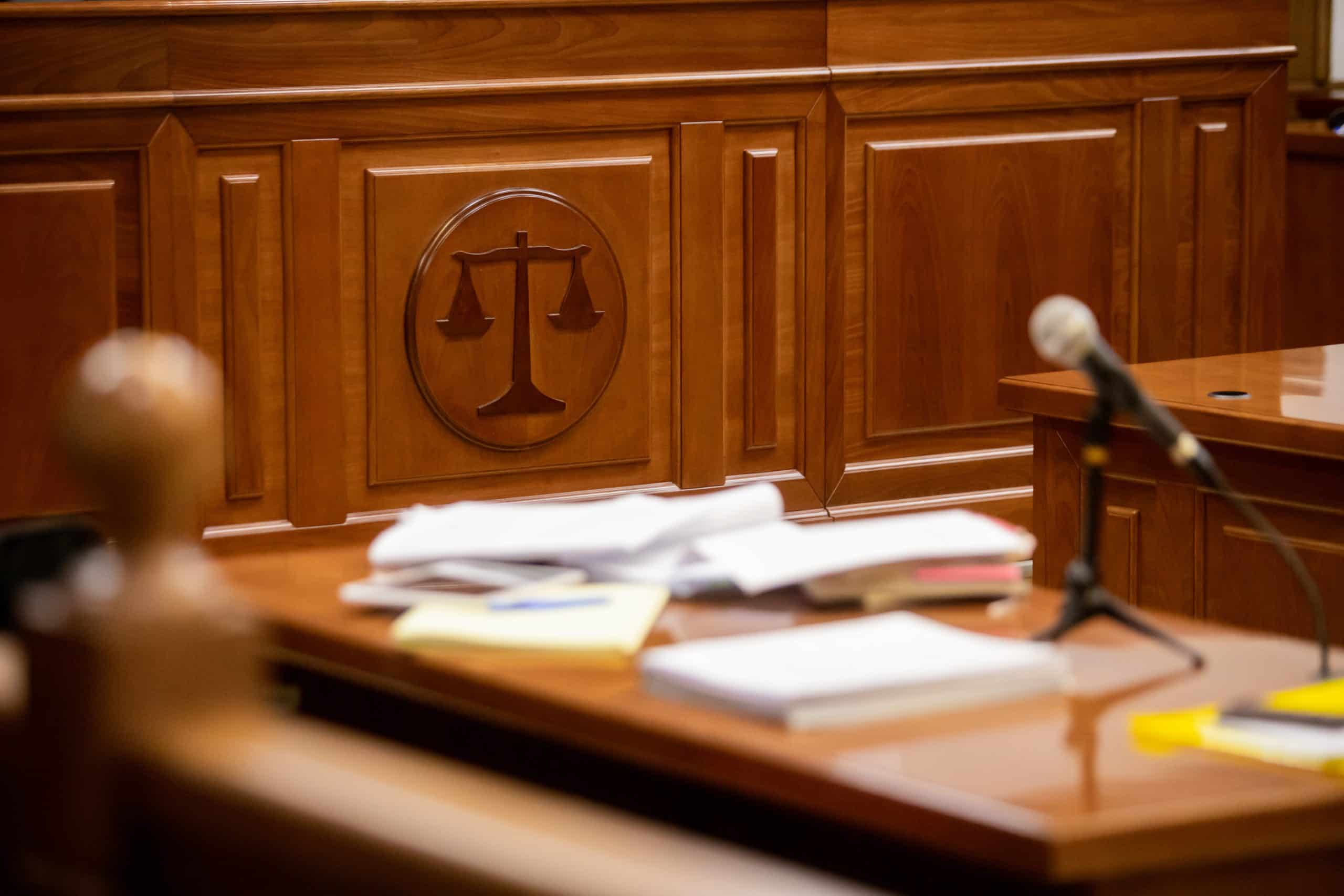 Balance sign in a wood courtroom with papers on a desk